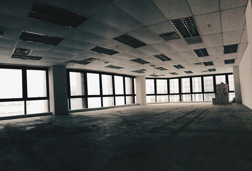 An empty office floor with exposed ceiling grid and large windows, ready for a fit-out (illustrative)